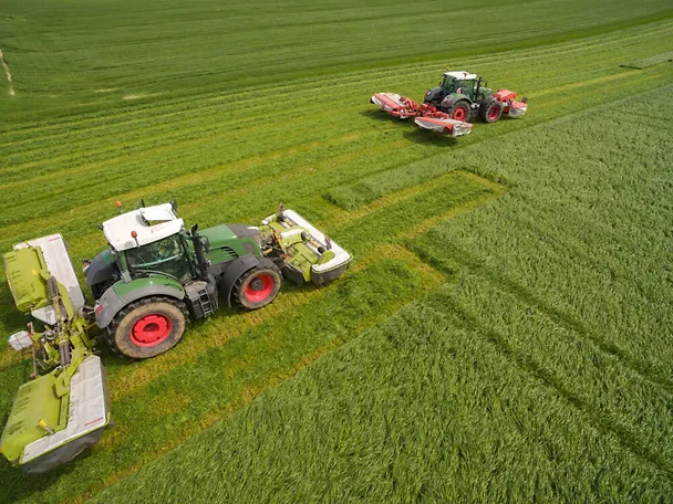 Zwei Traktoren beim Gras mähen