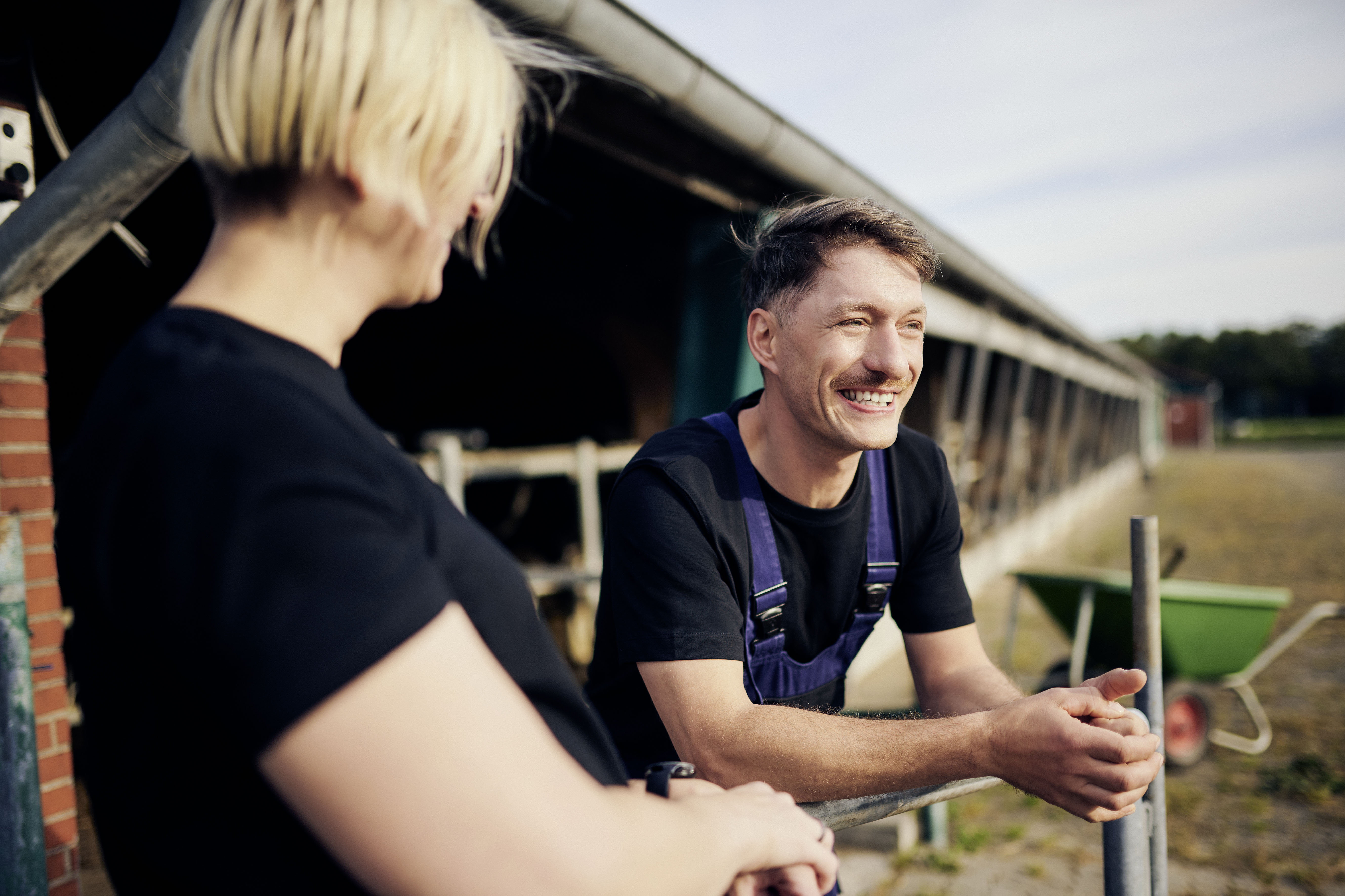 Zwei Personen unterhalten sich neben einem Kuhstall Zwei Personen unterhalten sich neben einem Kuhstall